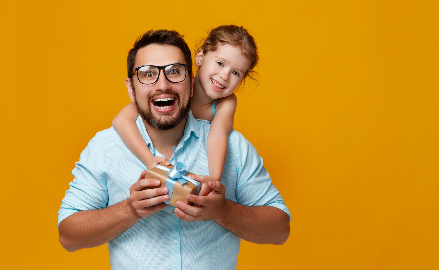 happy father's day! cute dad and daughter hugging on yellow background